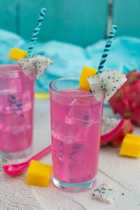 Two glasses with straws decorated with dragonfruit and filled with a bright pink drink